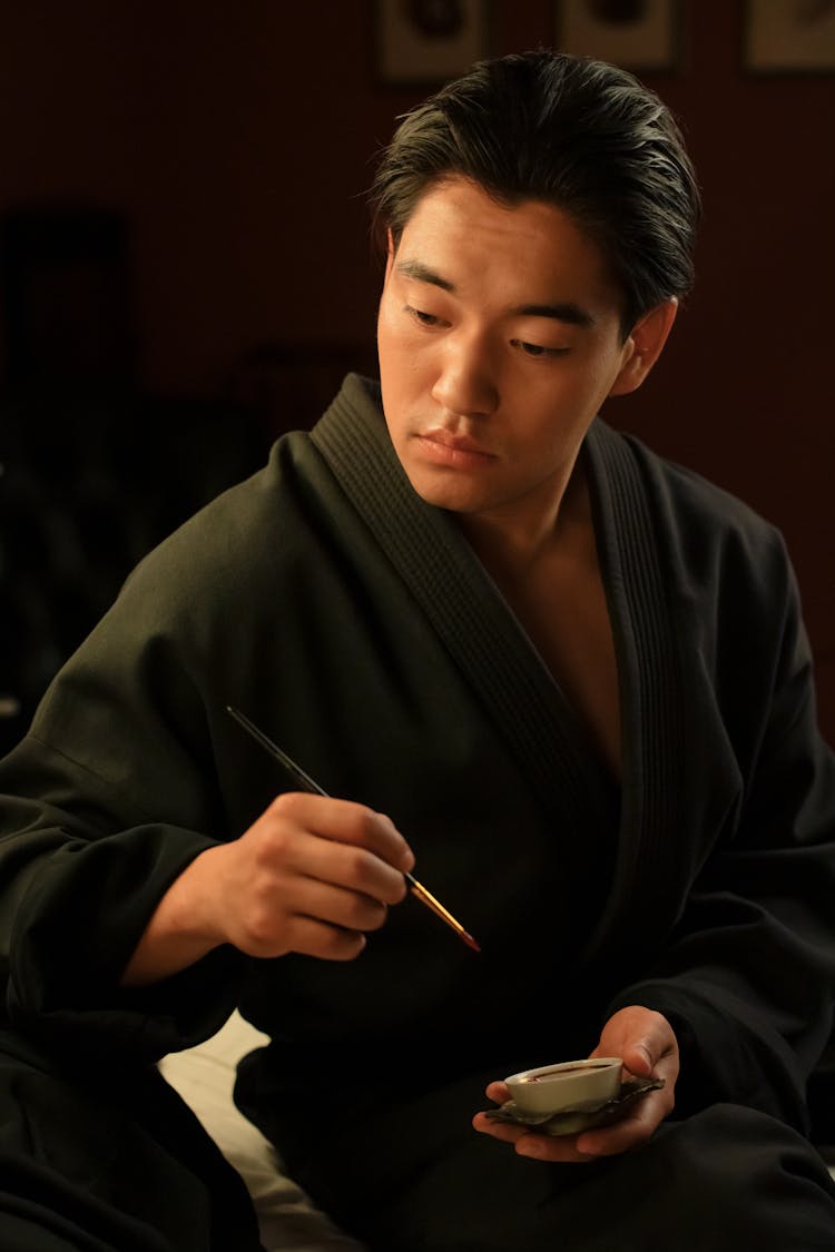 Man In Black Robe Holding A Paintbrush