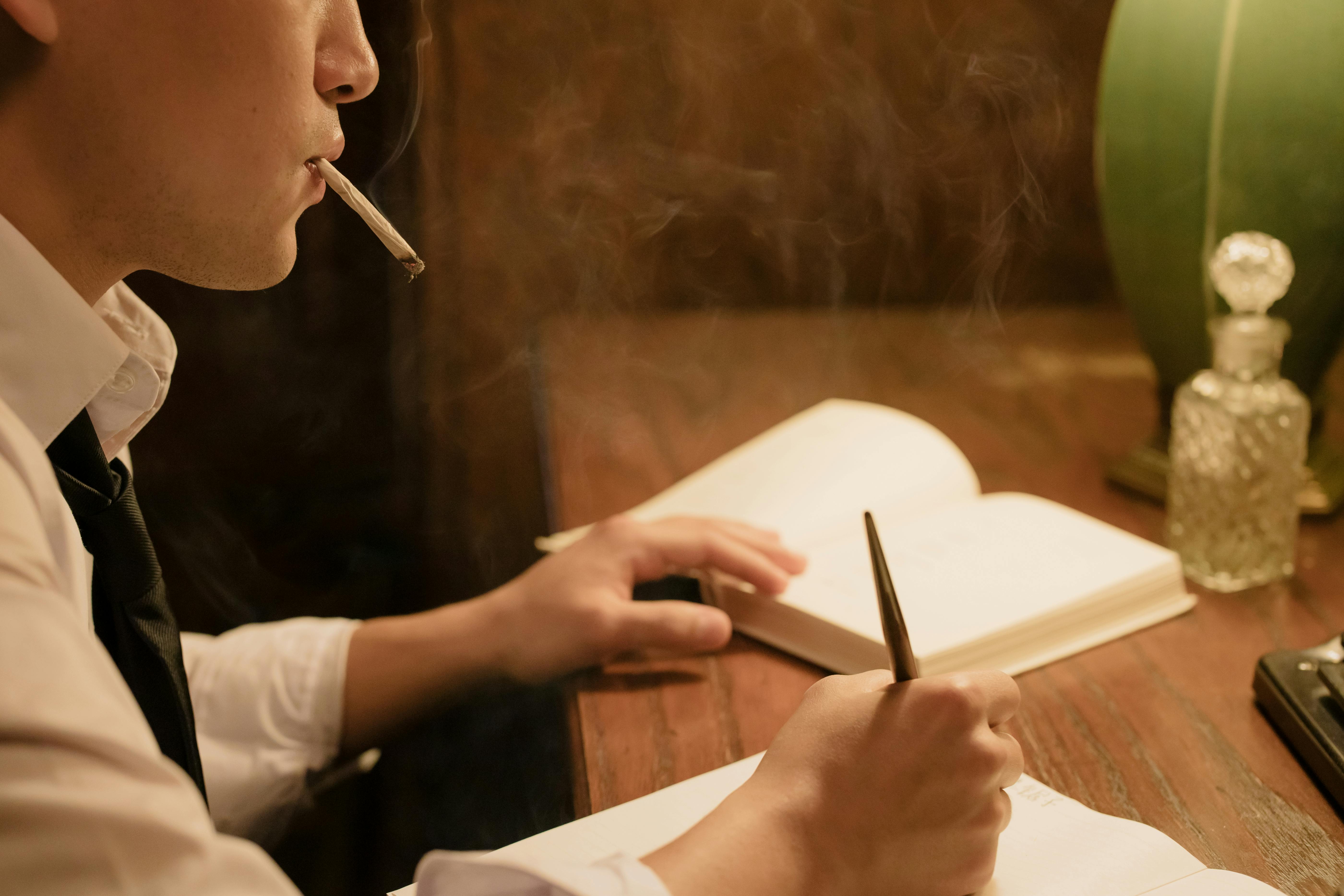 man smoking and writing on his notebook