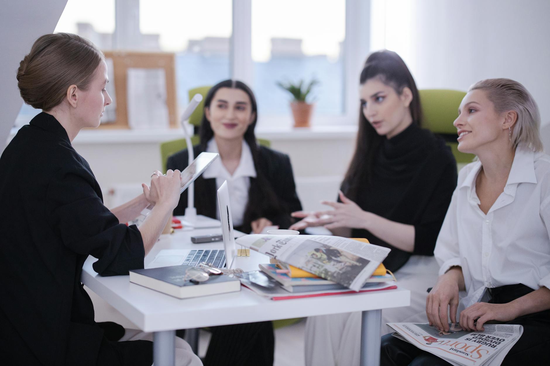 Group of diverse professionals in a lively office meeting, engaged in conversation and planning.