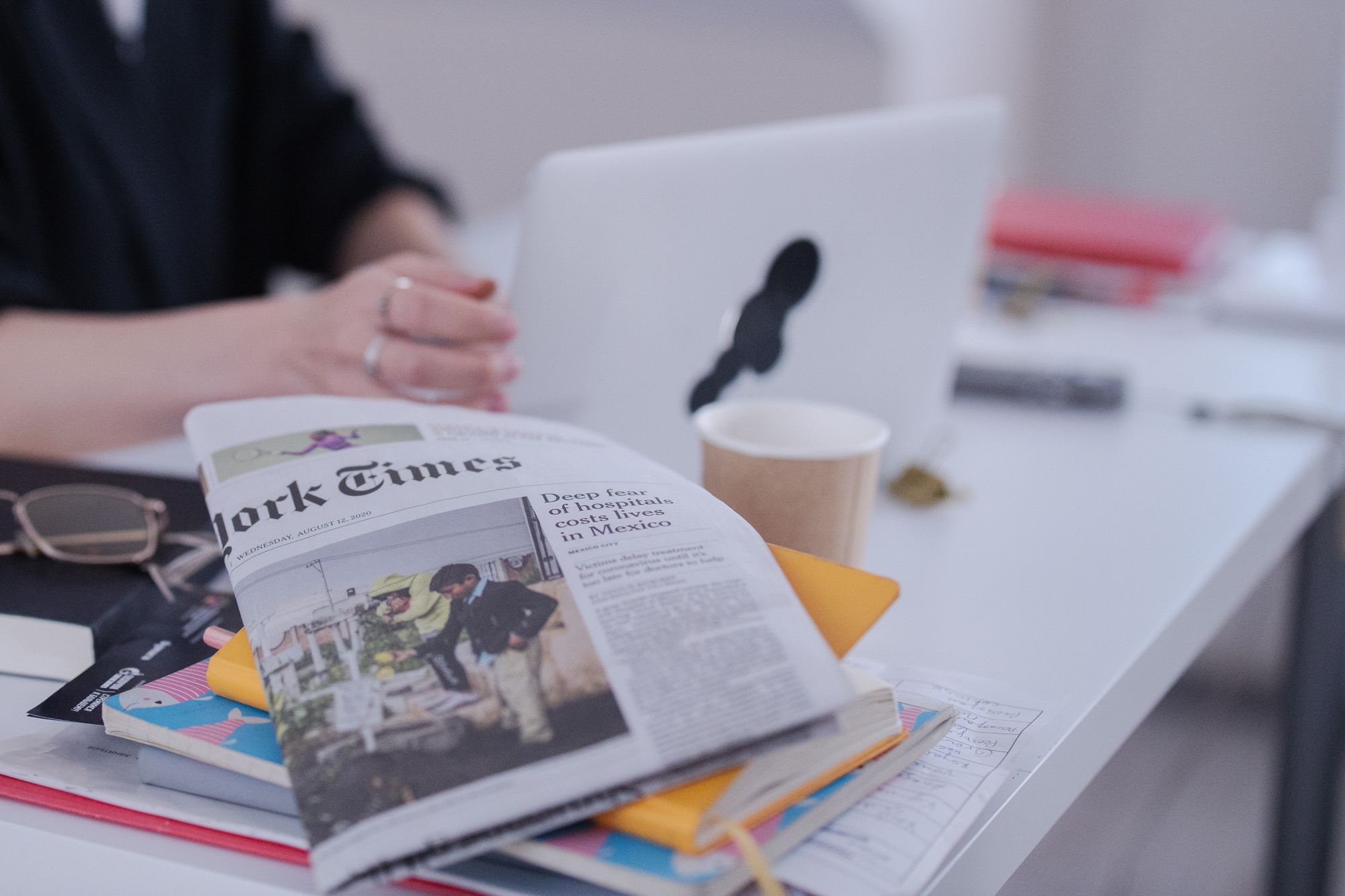 A newspaper, books, and desk materials arranged in an editorial workspace
