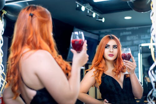 Redhead Woman in Black Sleeveless Dress Holding Wine in Glass