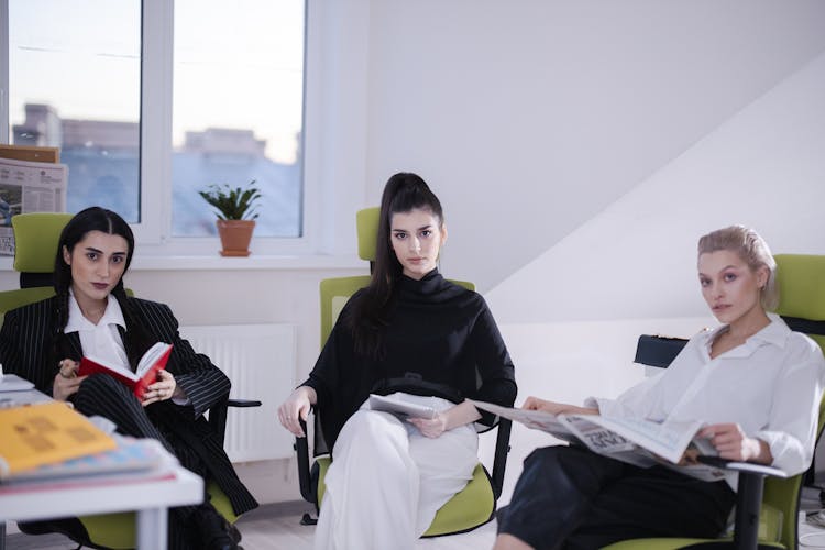 A Group Of Women Sitting On The Chair While Looking With A Serious Face