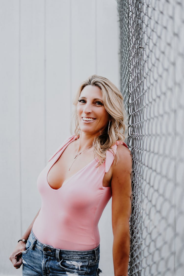 Cheerful Woman In Stylish Apparel Against Grid Fence