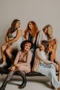 Group of cheerful models with different body types hairstyles and outfits sitting on couch in studio against gray background