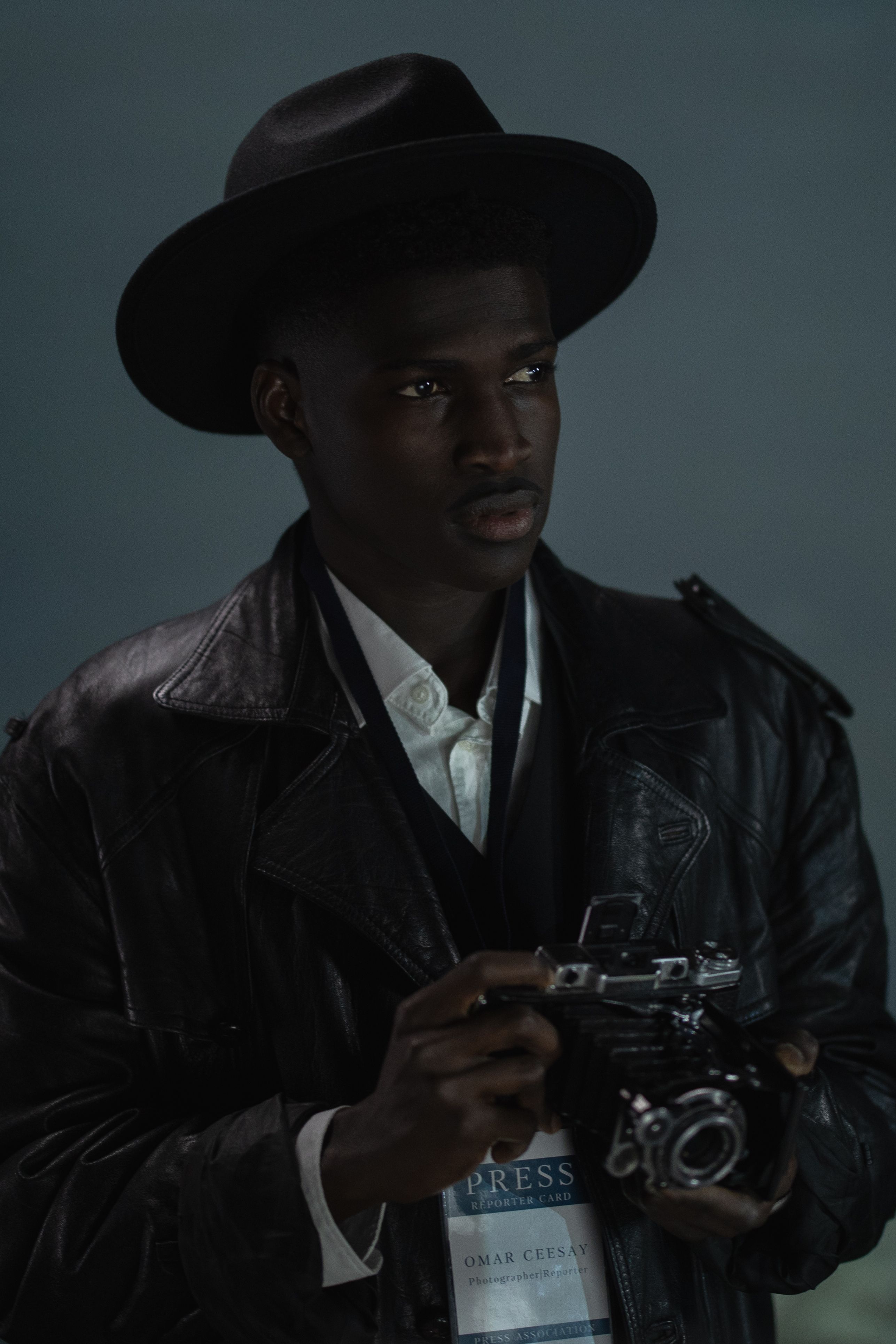 A stylish man in a fedora hat with a vintage camera, perfect for editorial use.