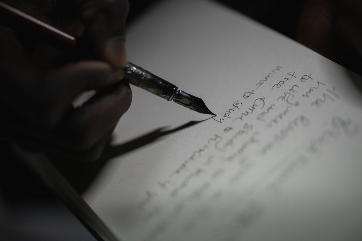万年筆で紙に文字を手書きしている手元