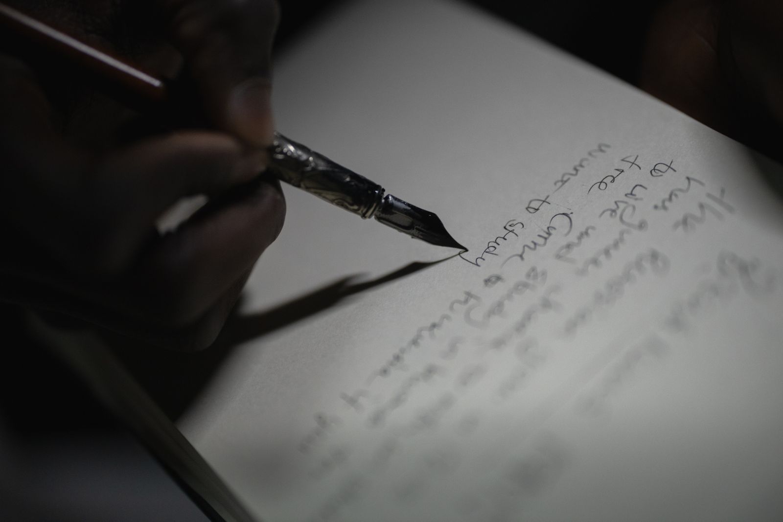 A hand writing with a fountain pen on paper.