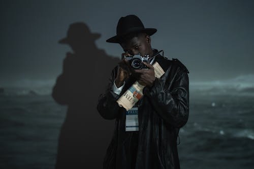 Man in a Black Hat and Black Leather Jacket Holding a Camera