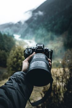 Photographer holding camera focused on a misty mountain valley.
