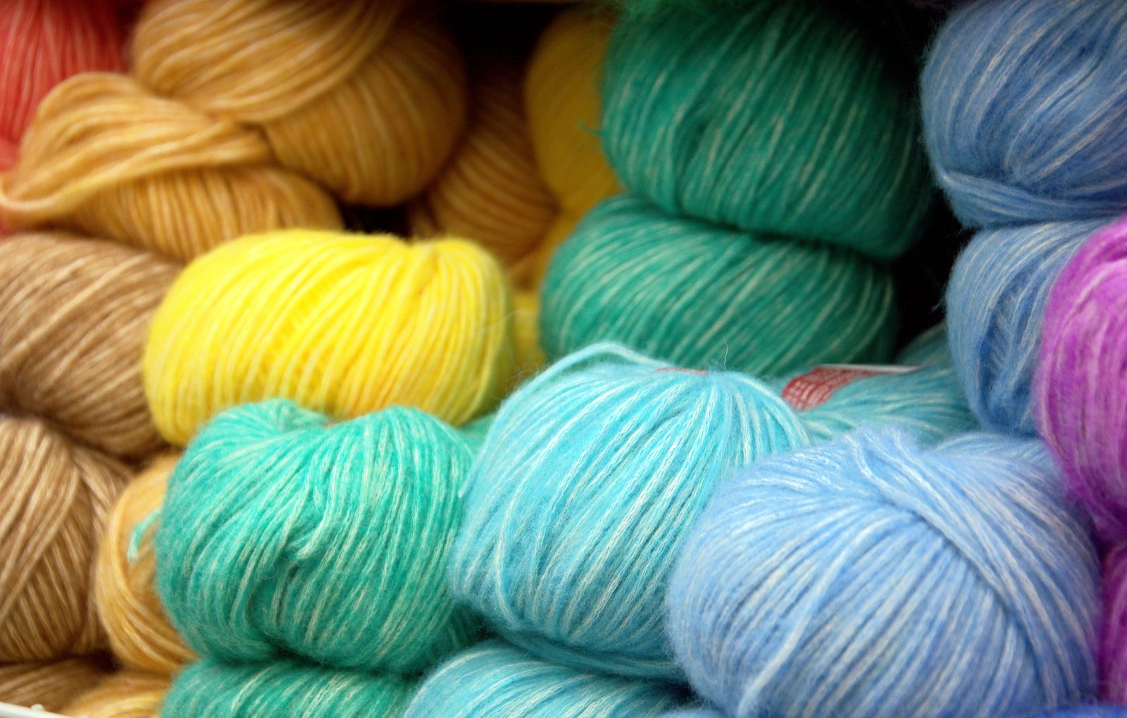 Close-up of several balls of colorful wool yarn in a craft basket