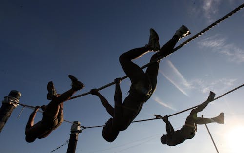 Free Трое мужчин поднимаются по веревке на закате Stock Photo
