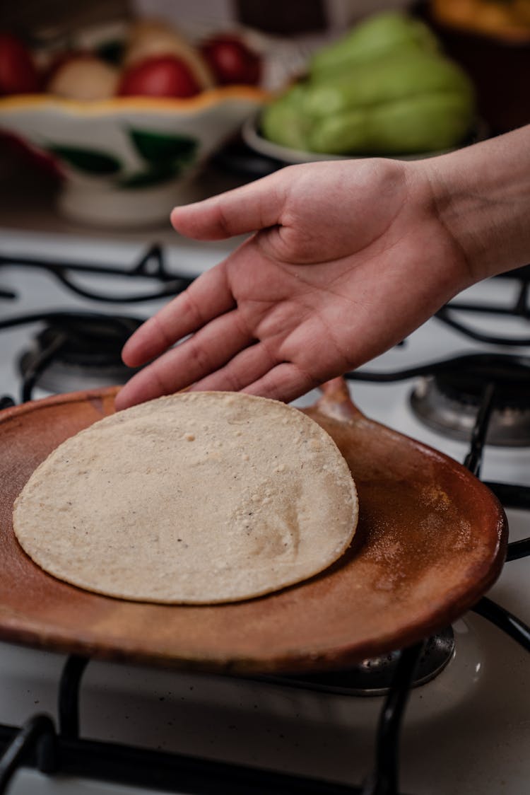 Person Holding A Tortilla On Brown Wooden Plate