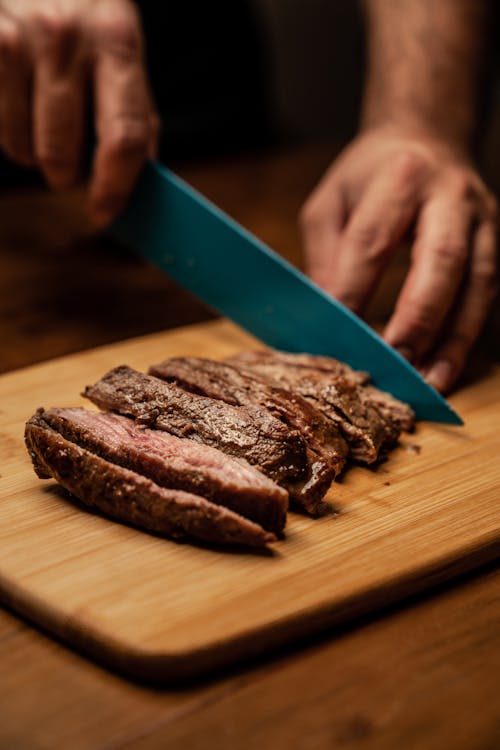 Free Person Slicing Meat on Brown Chopping Board Stock Photo