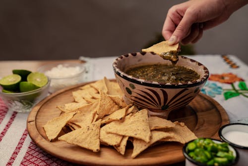 A Person Dipping Chips on Salsa 