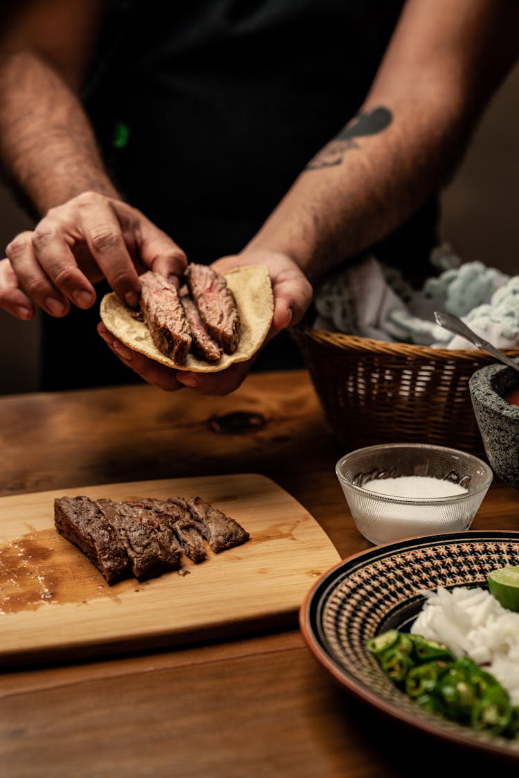 Person Putting Sliced Beef Steak On Tortilla