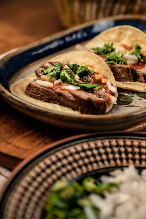 Free Close-up of delicious steak tacos garnished with fresh cilantro and onions on a rustic plate. Stock Photo