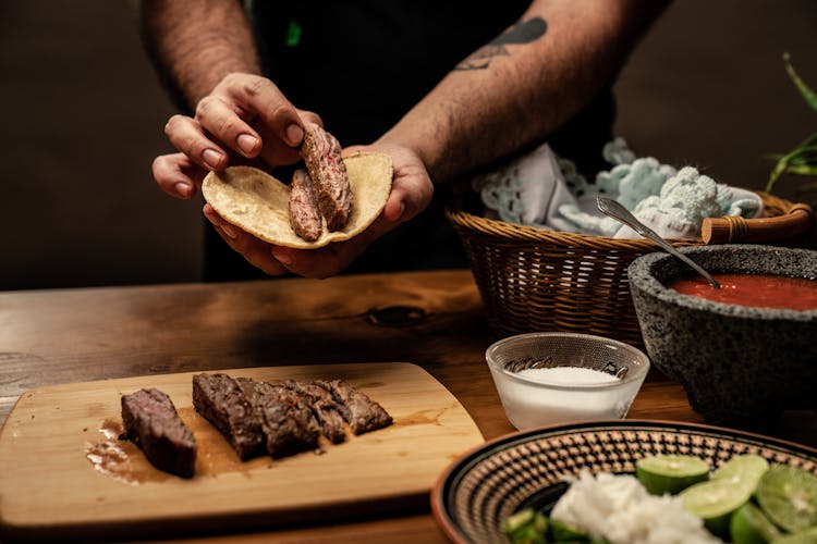 Person Putting Sliced Beef Steak On Tortilla