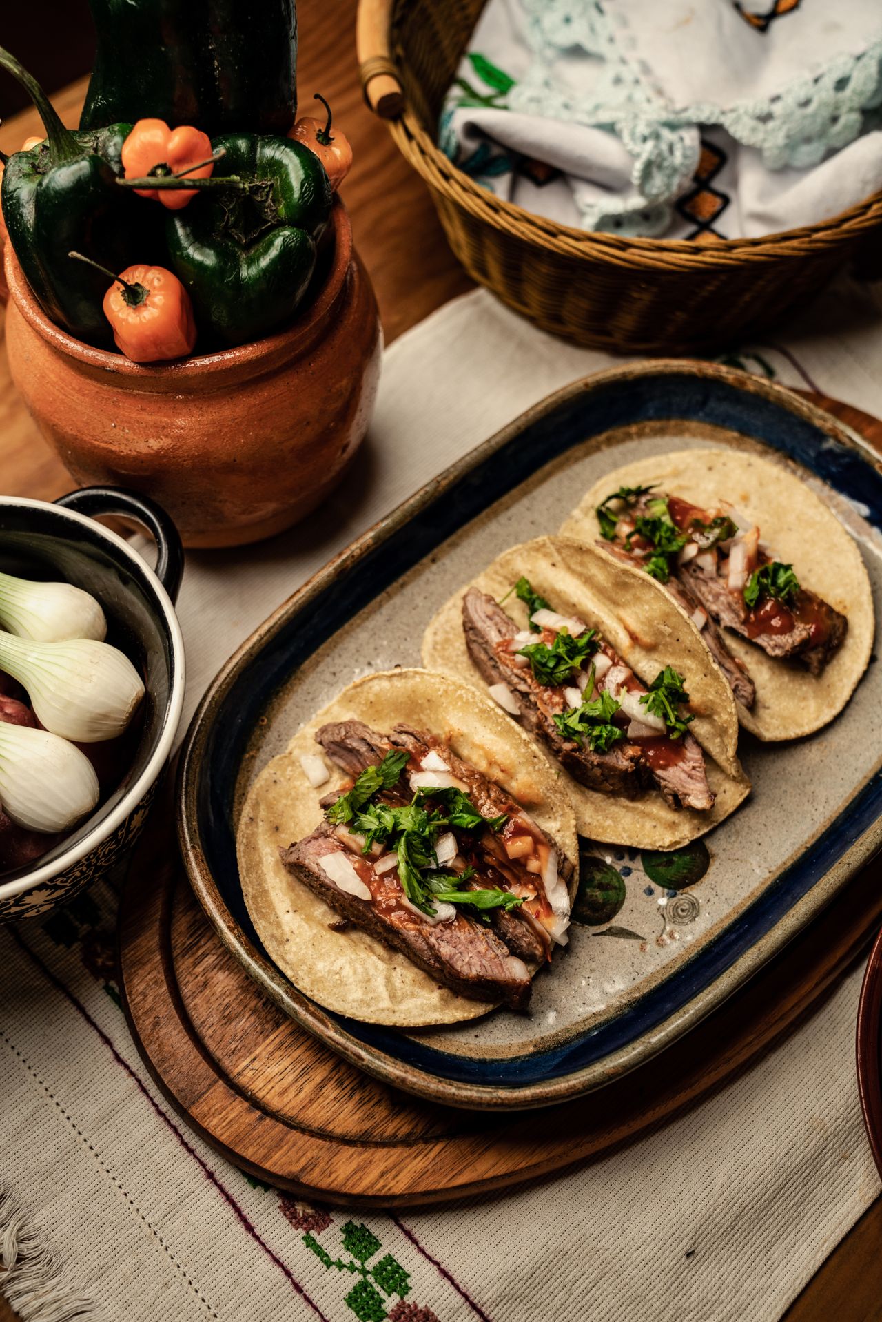 Mexican shredded beef tacos served on a rustic platter with fresh onions and cilantro