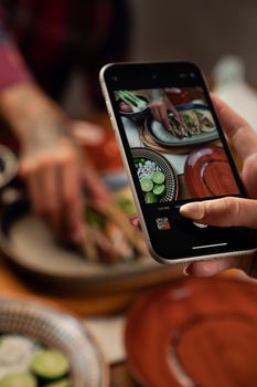 Person photographing Mexican tacos with a smartphone in a kitchen setting.