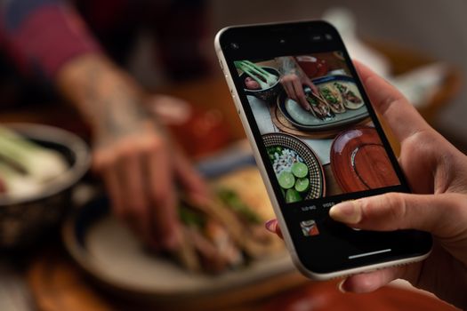 Person photographing delicious Mexican tacos with a smartphone.