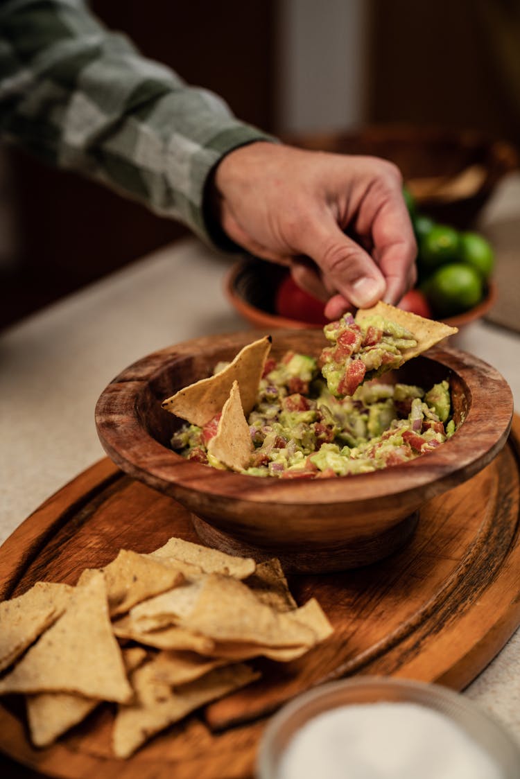 Male Hand Taking Chips From Bowl With Salad