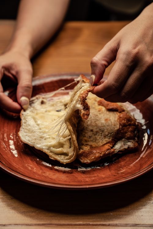 Free A close-up of hands preparing a traditional Mexican cheese quesadilla on a rustic plate. Stock Photo