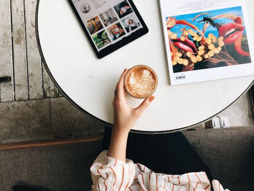 Free Overhead view of a cozy coffee break with latte, tablet, and magazine on a stylish round table. Stock Photo