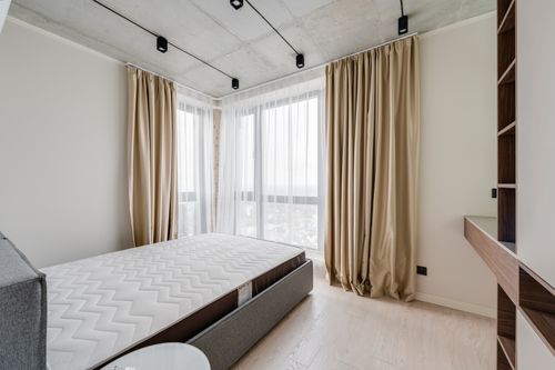 Free Spacious modern bedroom with cozy bedding and natural light. Stock Photo