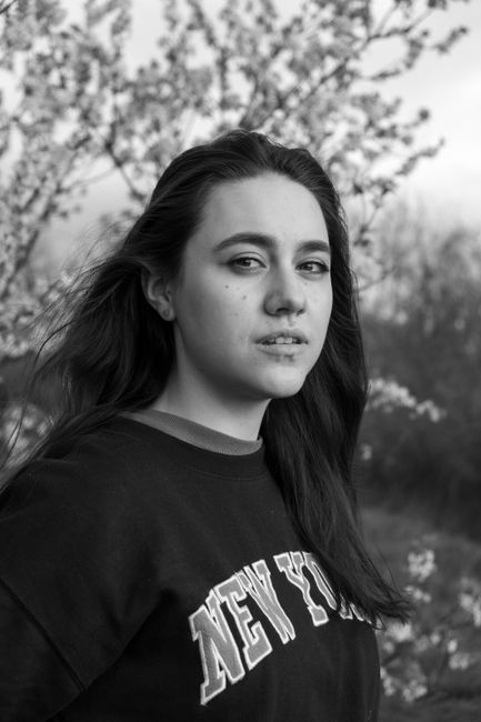 Thoughtful woman posing outdoors with flowers in black and white.