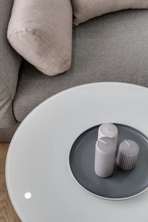 Free A modern grey couch with decorative candles on a sleek round table in a minimalist setting. Stock Photo