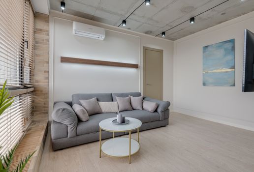 Stylish living room with a gray sofa, abstract art, and minimalist design.