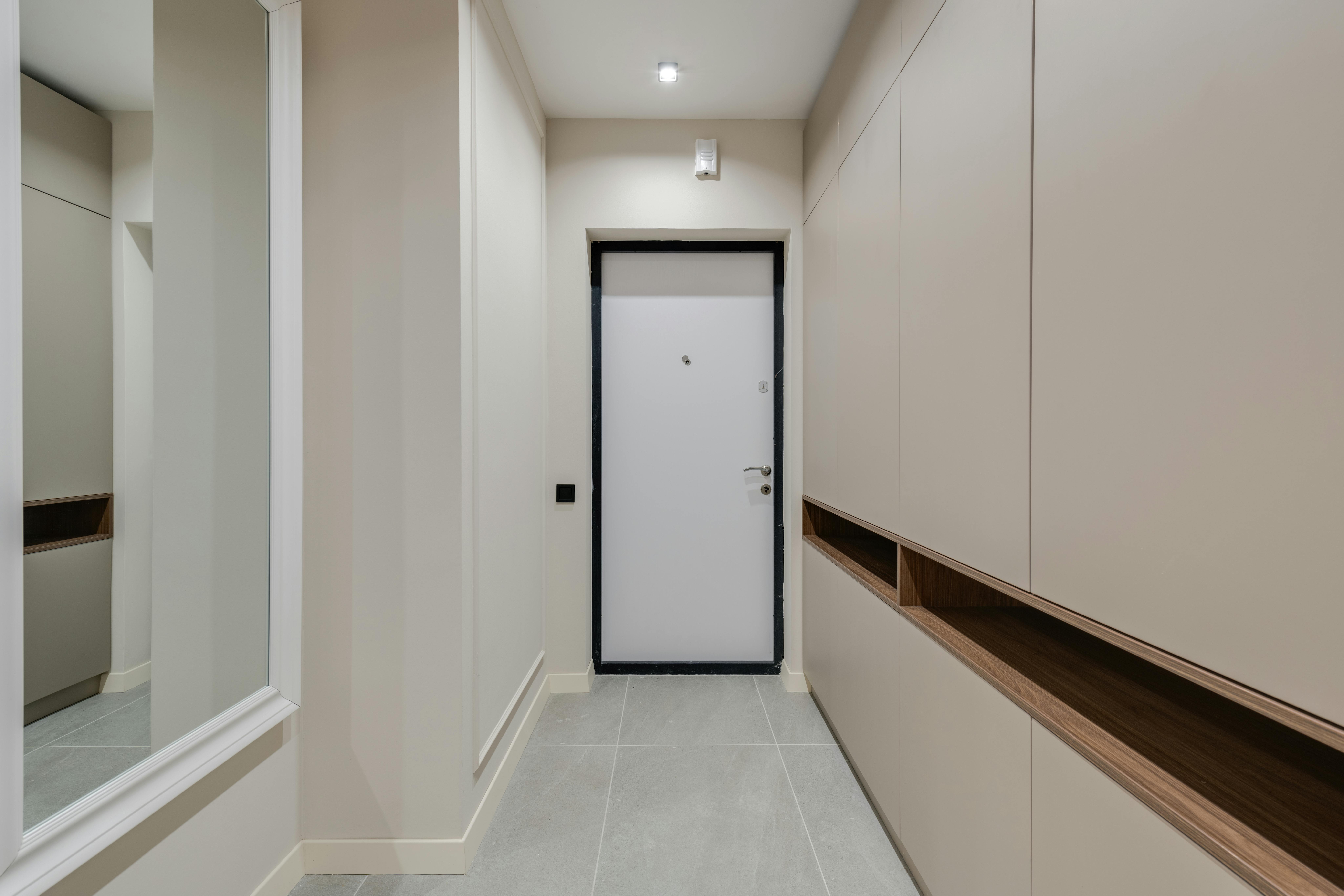 Einbauschrank unter einer Holztreppe im Flur mit geschlossenen weißen Fronten und Sitzbank