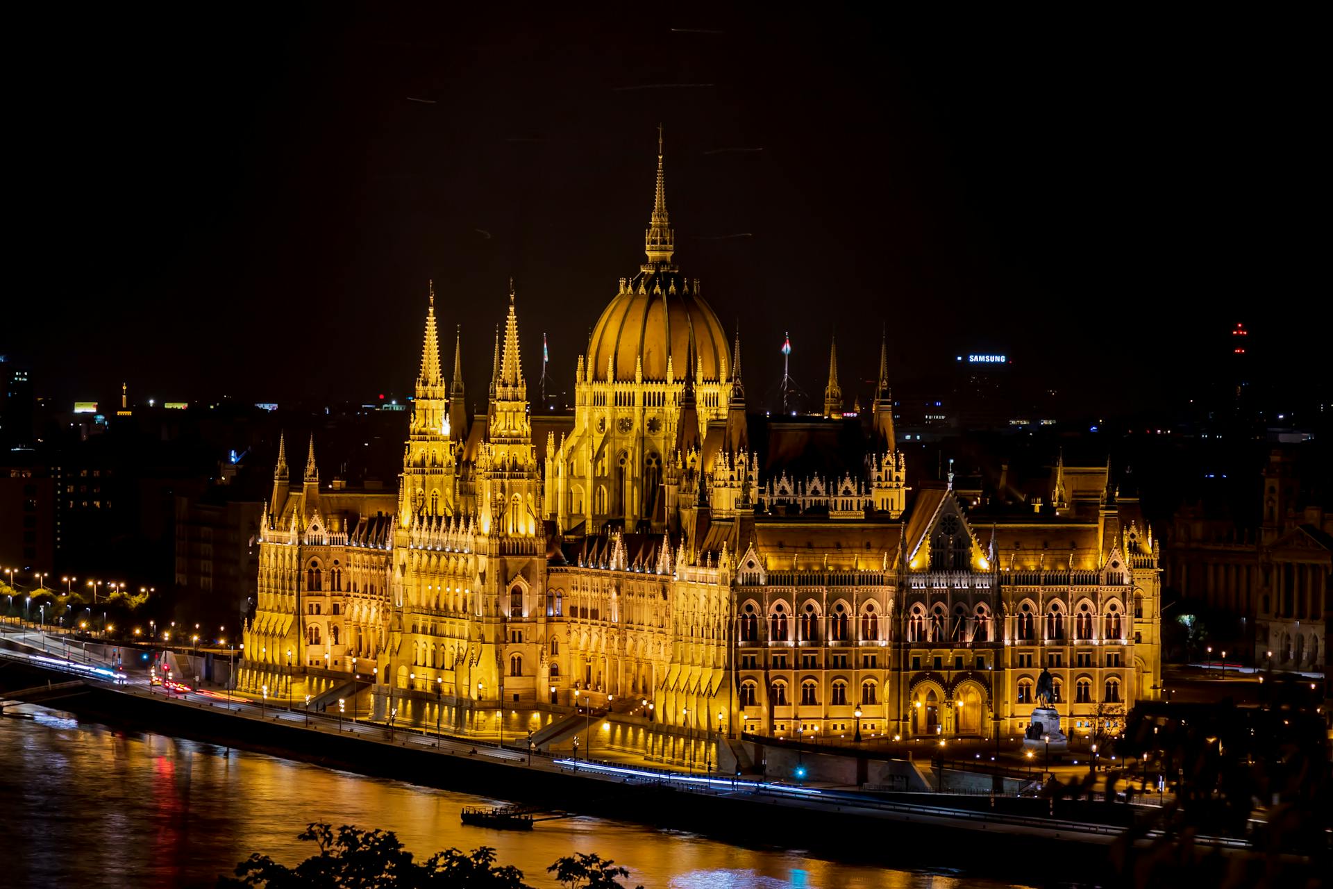 Illuminated Gothic building with glowing lights on river bank