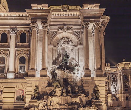 Famous landmark of Budapest aged Matthias Fountain in courtyard of Buda Palace with group statues at night