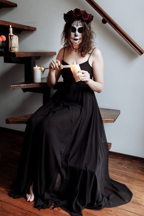 Free Woman in black dress with skull makeup holding candles, celebrating Dia de los Muertos. Stock Photo