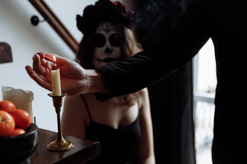 Free An artistic depiction of a Dia de los Muertos ritual with intricate face paint and candle lighting. Stock Photo