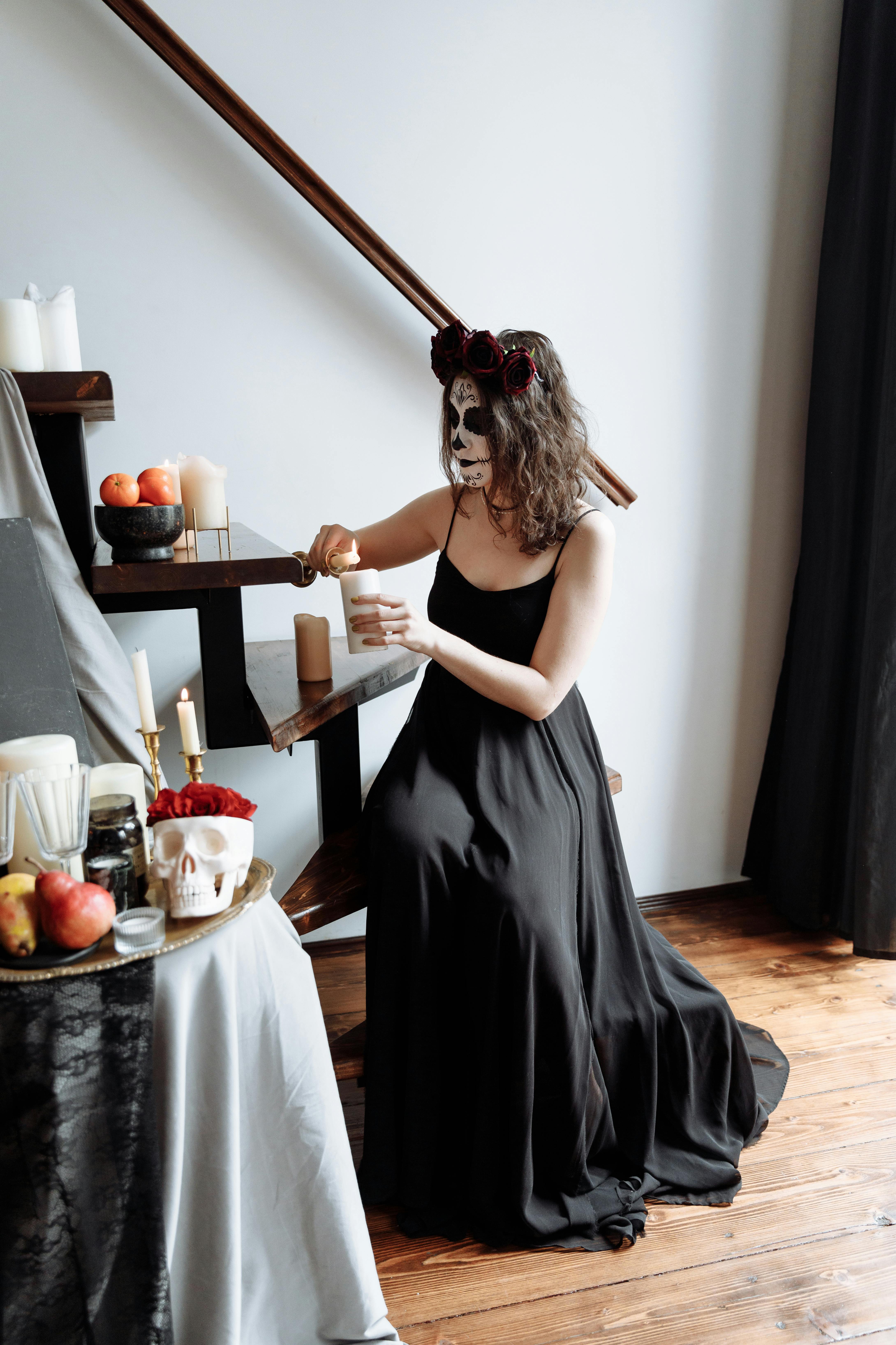 woman in black dress lighting up a candle while sitting on the stairs