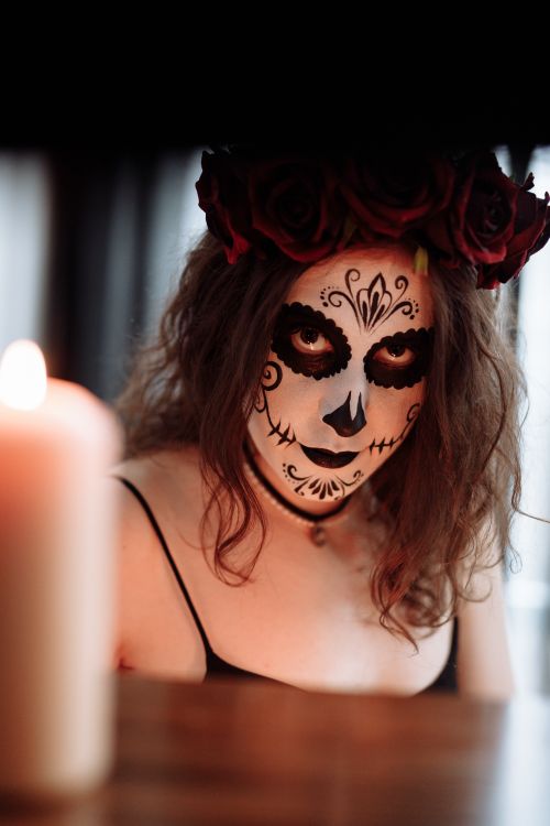 Free A woman with elaborate sugar skull makeup celebrates Dia de los Muertos, adorned in a dark setting. Stock Photo