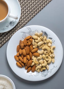 Flat lay of almonds and cashews on a decorative plate with coffee.