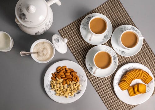 Free Close-Up Shot of a Cups of Coffee beside a Plate with Nuts Stock Photo
