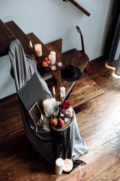 Free An elegant indoor setting with candles, apples, and a guitar by wooden stairs, creating a warm ambiance. Stock Photo