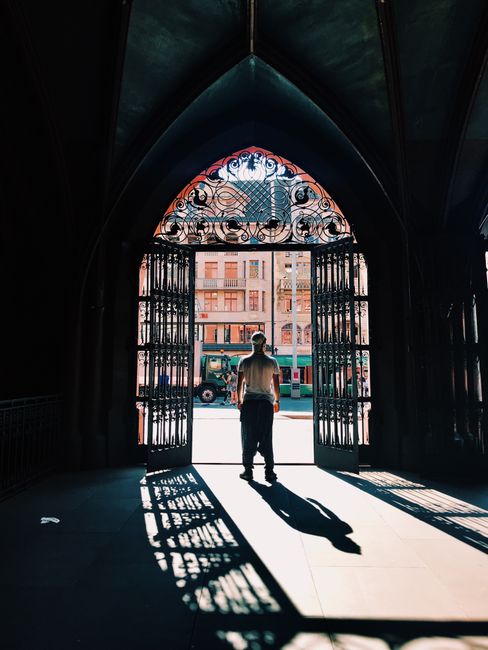 A man silhouetted against a bright background exits a gothic archway in Basel.