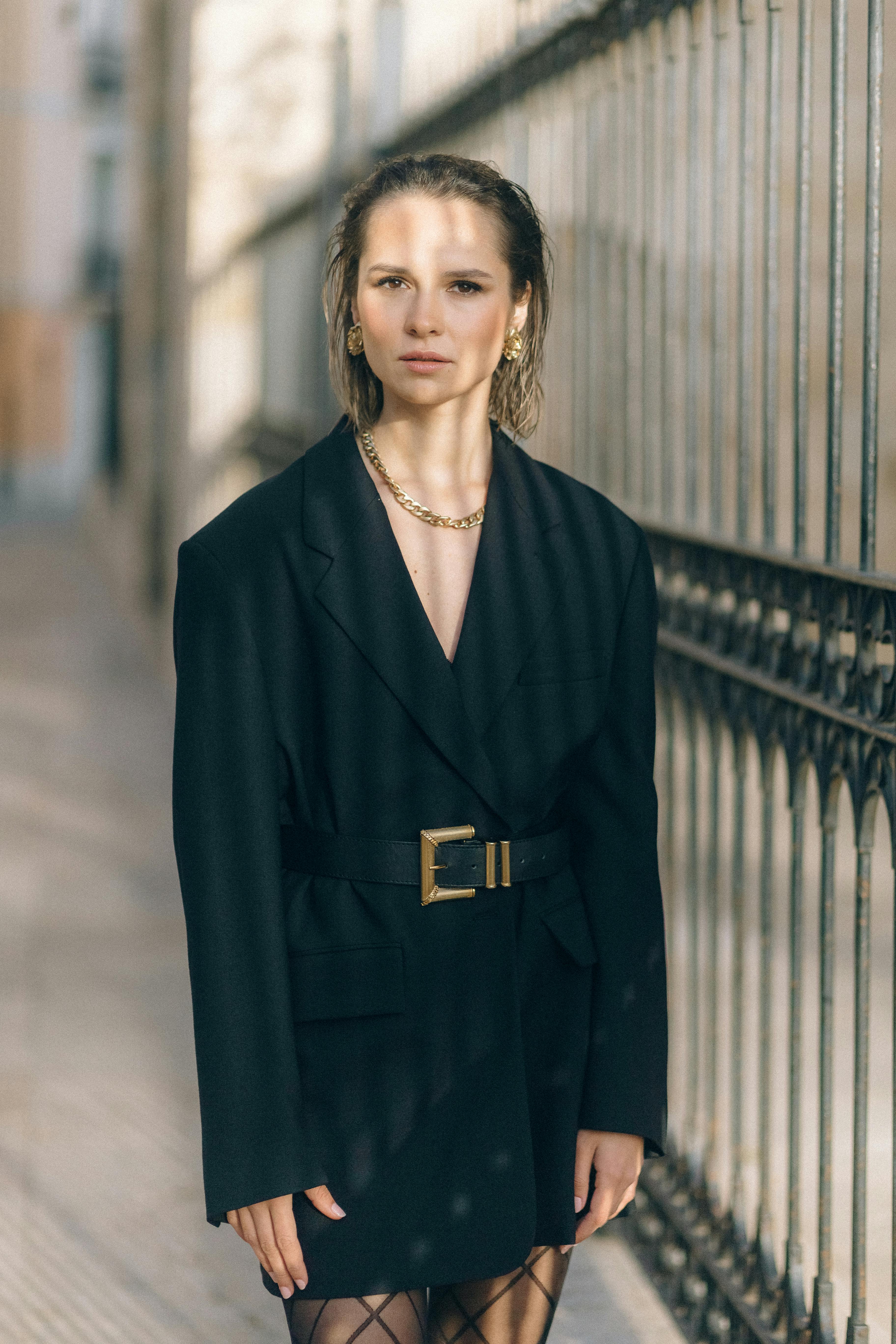 Free Fashionable woman in a blazer with gold chain posing outdoors Stock Photo