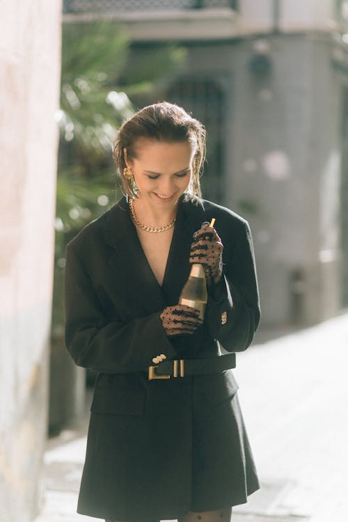 Woman in a Black Blazer Holding a Champagne Bottle