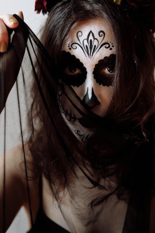 A Woman Wearing a Catrina Makeup Holding a Sheer Fabric near Face