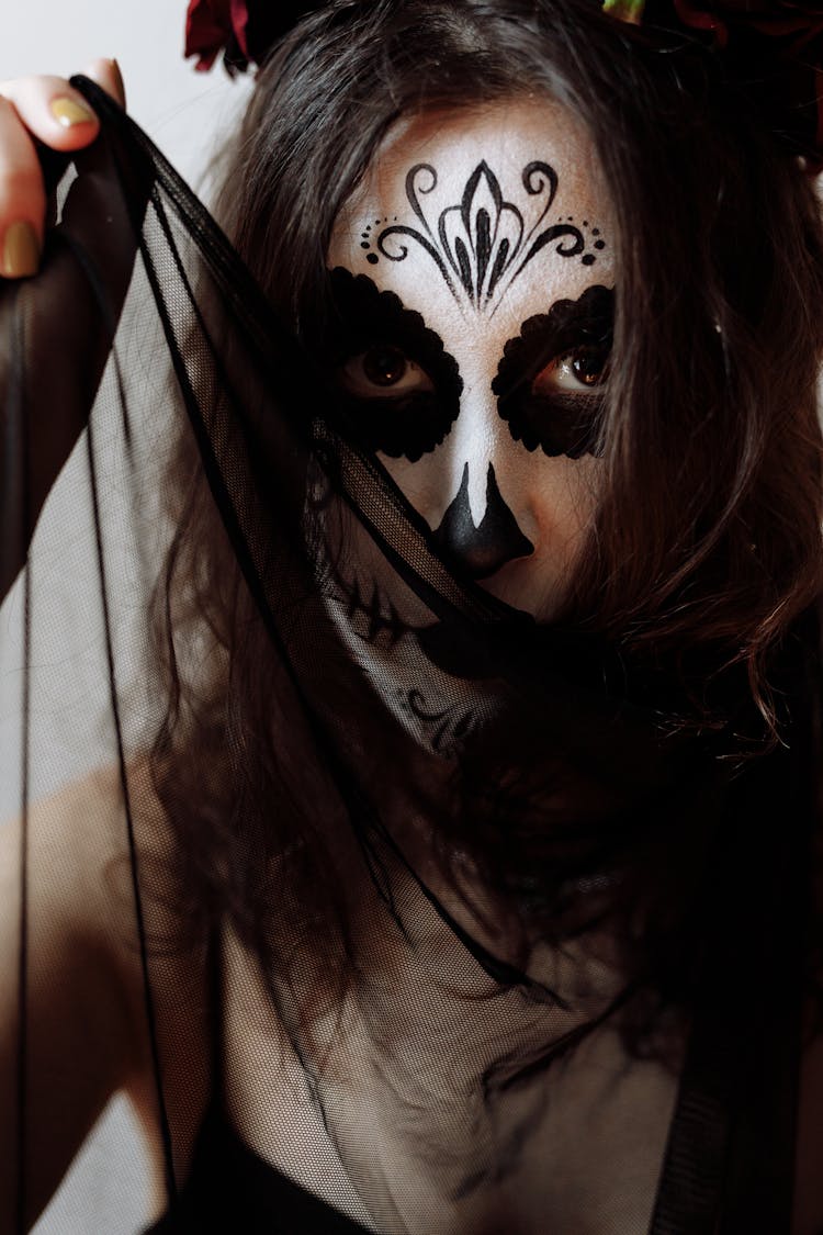 A Woman Wearing A Catrina Makeup Holding A Sheer Fabric Near Face