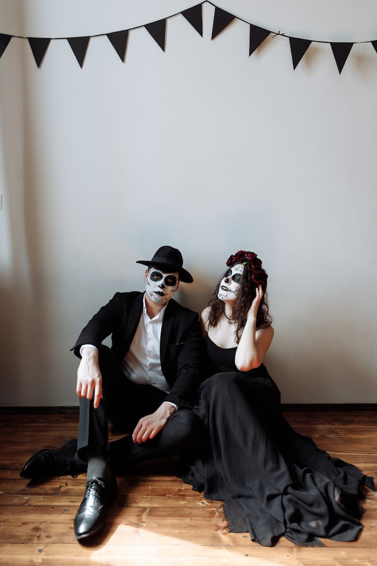 A Man And Woman With Skeleton Face Sitting On The Floor