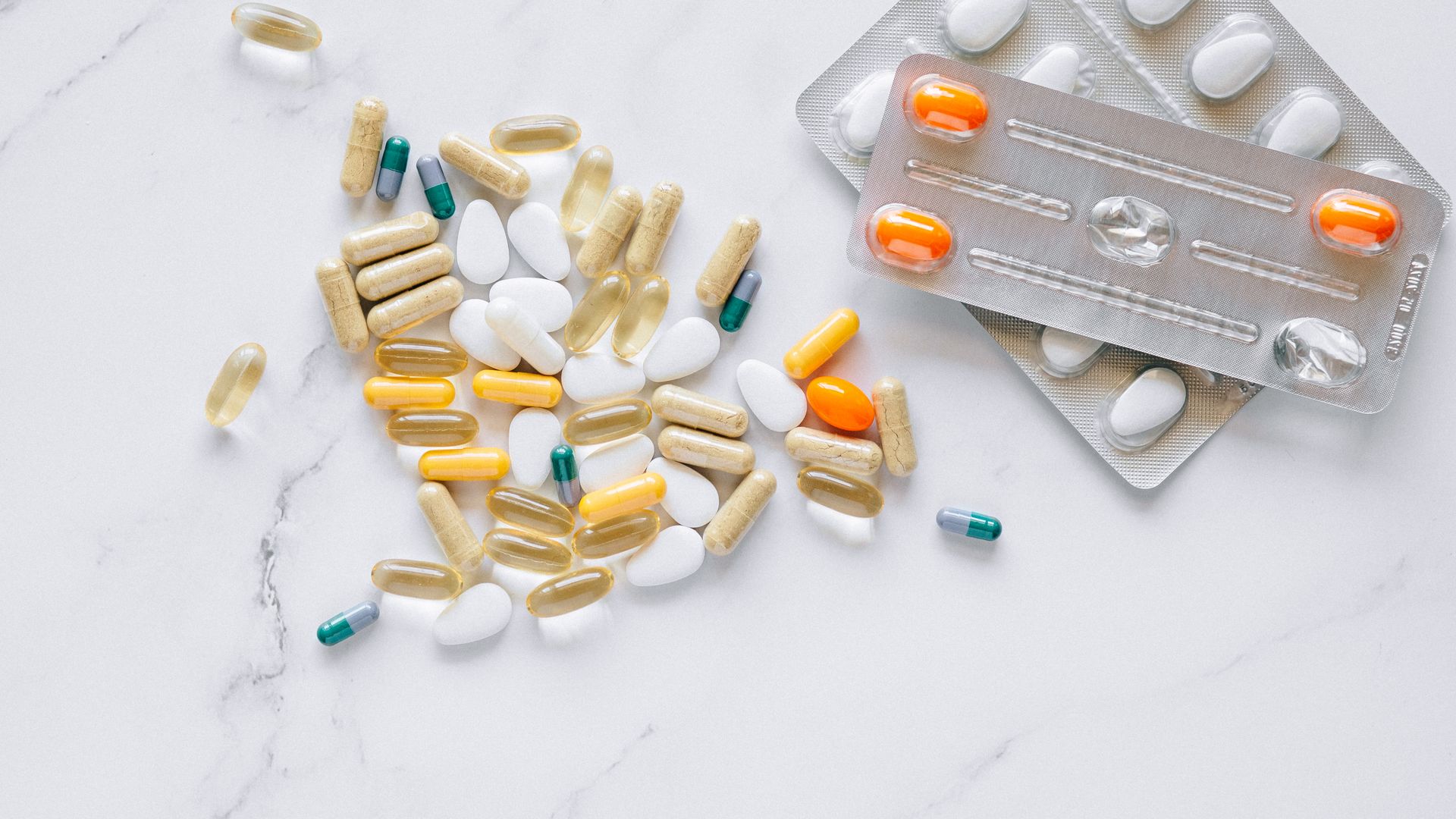 Armodafinil Benefits: Unlocking Cognitive Potential A variety of colored capsules and tablets arranged on a white marble surface, alongside blister packs — armodafinil benefits