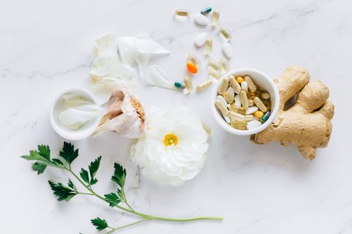 Free Top view of herbal medicine and supplements with ginger, flower, and capsules on a white background. Stock Photo