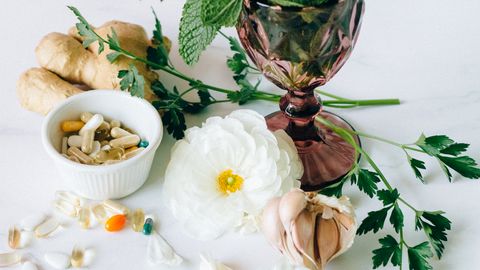 Arrangement of herbal medicine ingredients with capsules on marble surface for natural treatment.